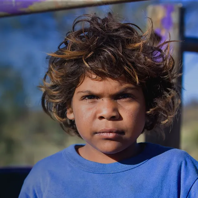 Young Aboriginal boy wearing a blue t-shirt looking at the camera