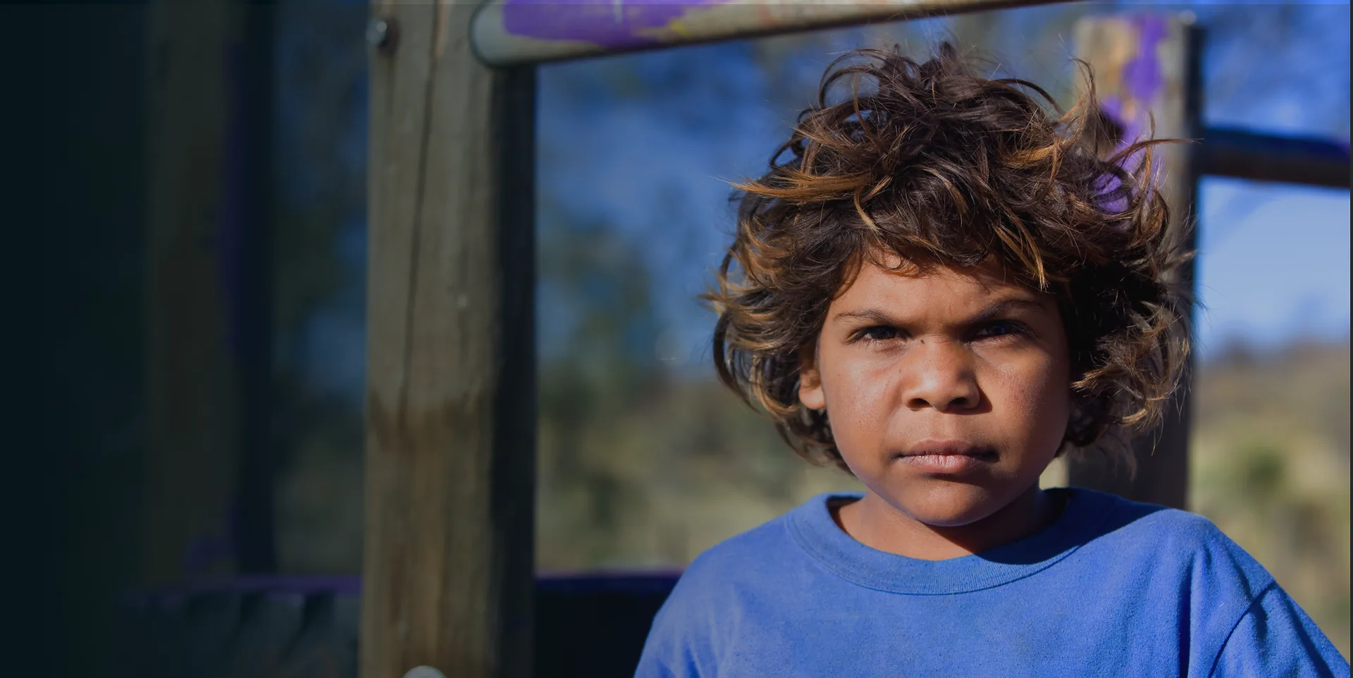 Young Aboriginal boy wearing a blue t-shirt looking at the camera